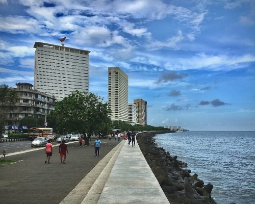 people walking on side walk beside beach