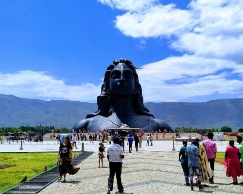 people standing around man's face statue in park